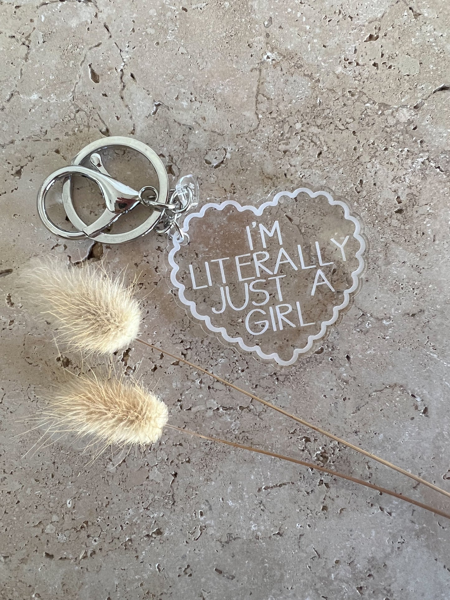 Keychain with 'I'm literally just a girl' tag on a concrete surface