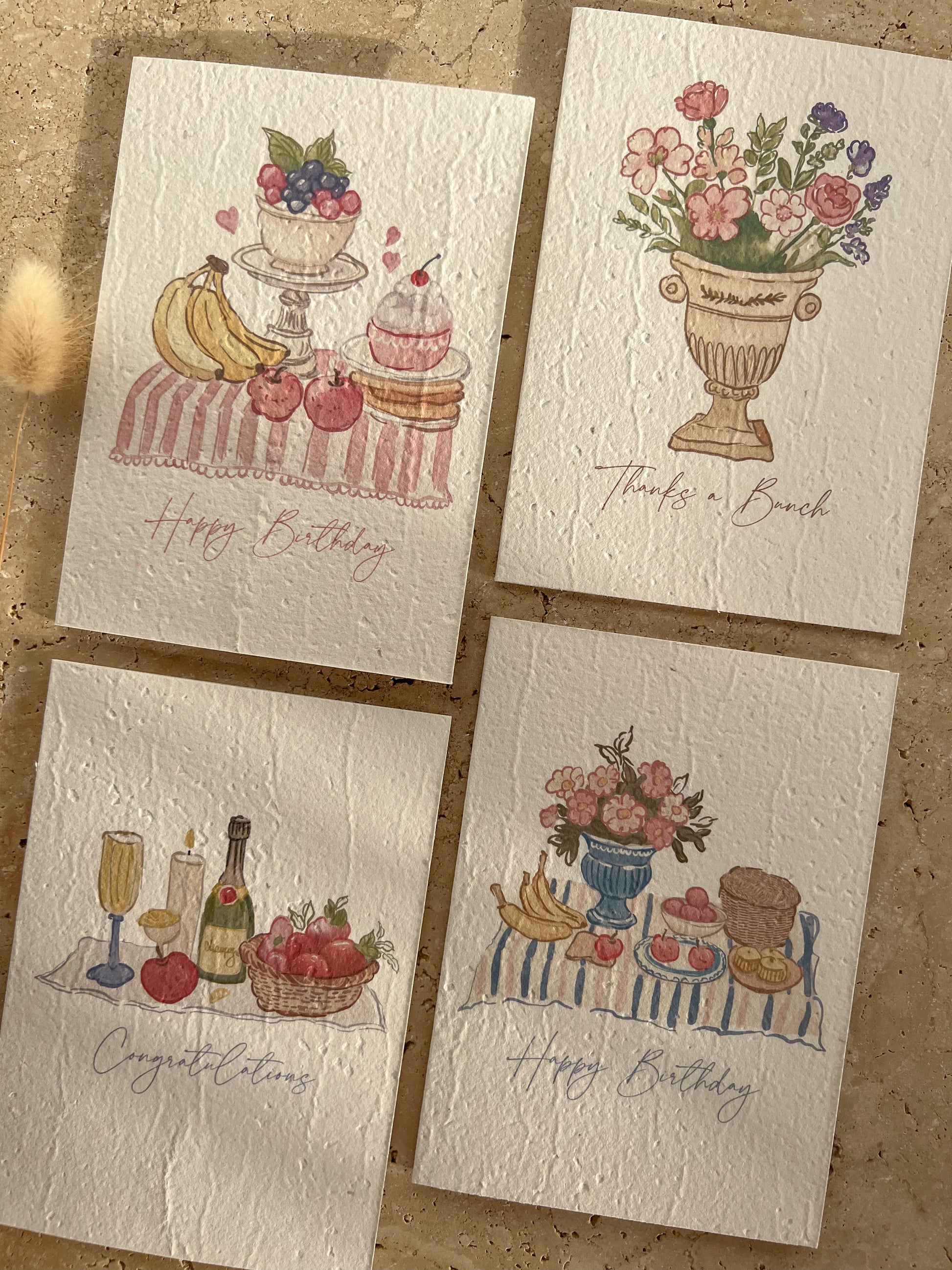 Four illustrated greeting cards on a textured surface