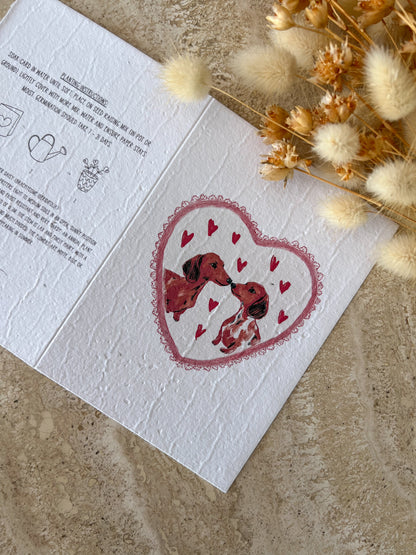 Greeting card with heart design and two dachshund dogs inside, surrounded by dried flowers on a textured surface, by Willow & Sage Co.