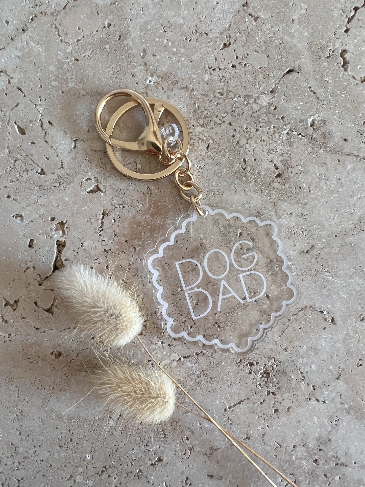 Keychain with 'Dog Dad' tag on a textured surface