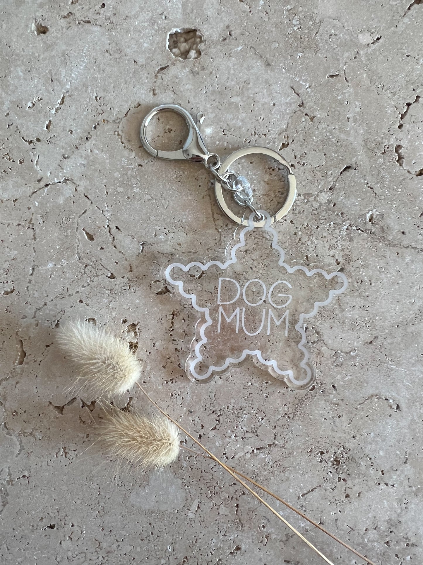 Clear star-shaped keychain with 'DOG MUM' text on a textured surface.