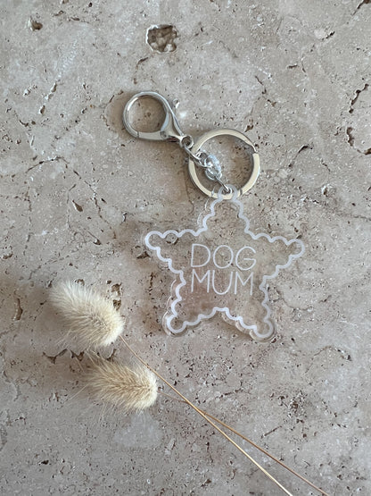 Clear star-shaped keychain with 'DOG MUM' text on a textured surface.