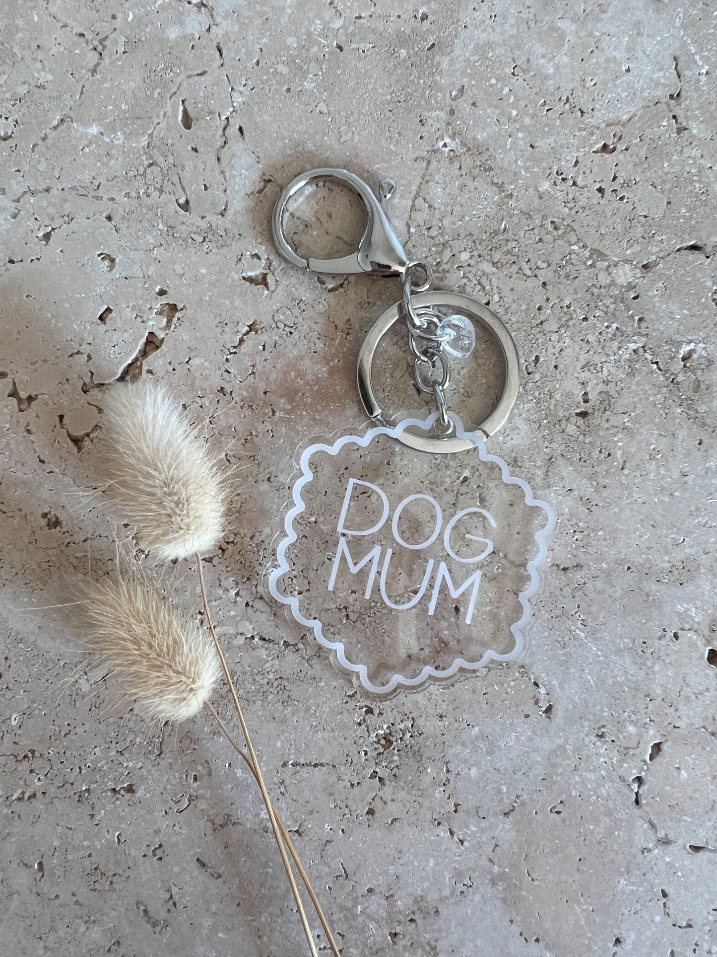 Keychain with 'DOG MUM' text on a textured surface with a dried plant.