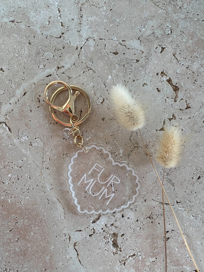 Gold keychain with 'Fur Mum' tag on a textured surface with dried grasses.