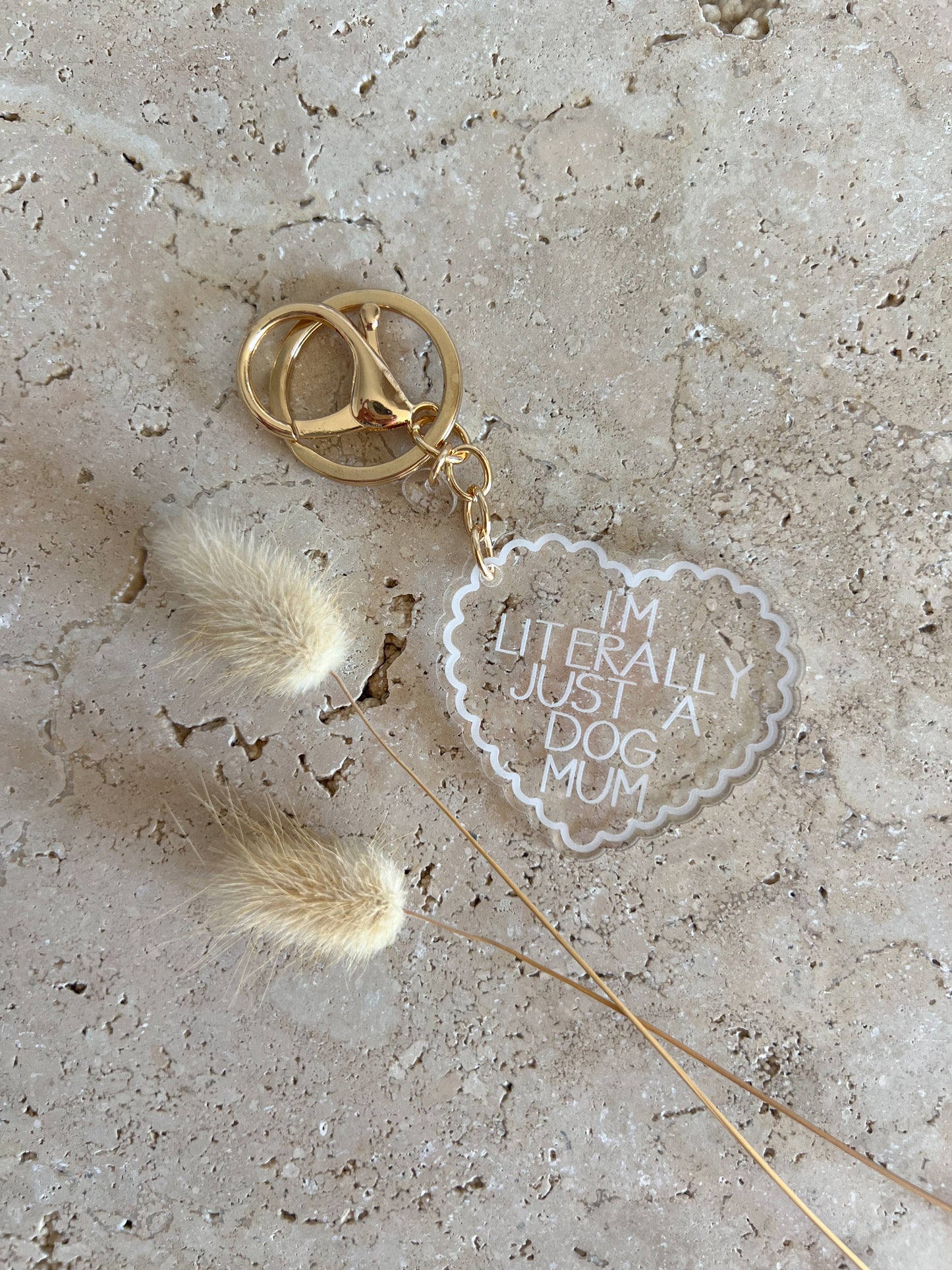 Keychain with heart-shaped tag reading 'I'm literally just a dog mum' on a textured surface.