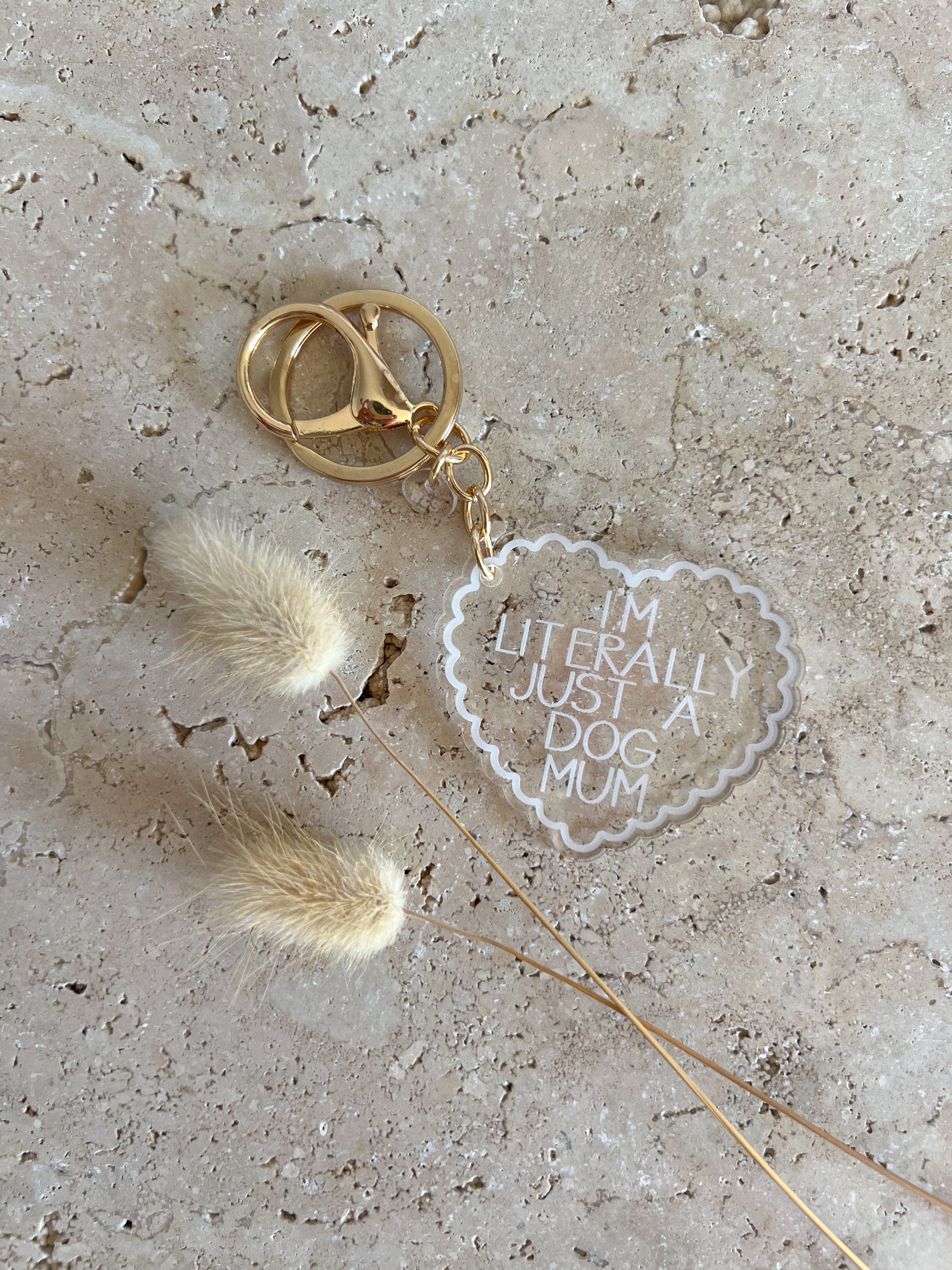 Keychain with heart-shaped tag reading 'I'm literally just a dog mum' on a textured surface.