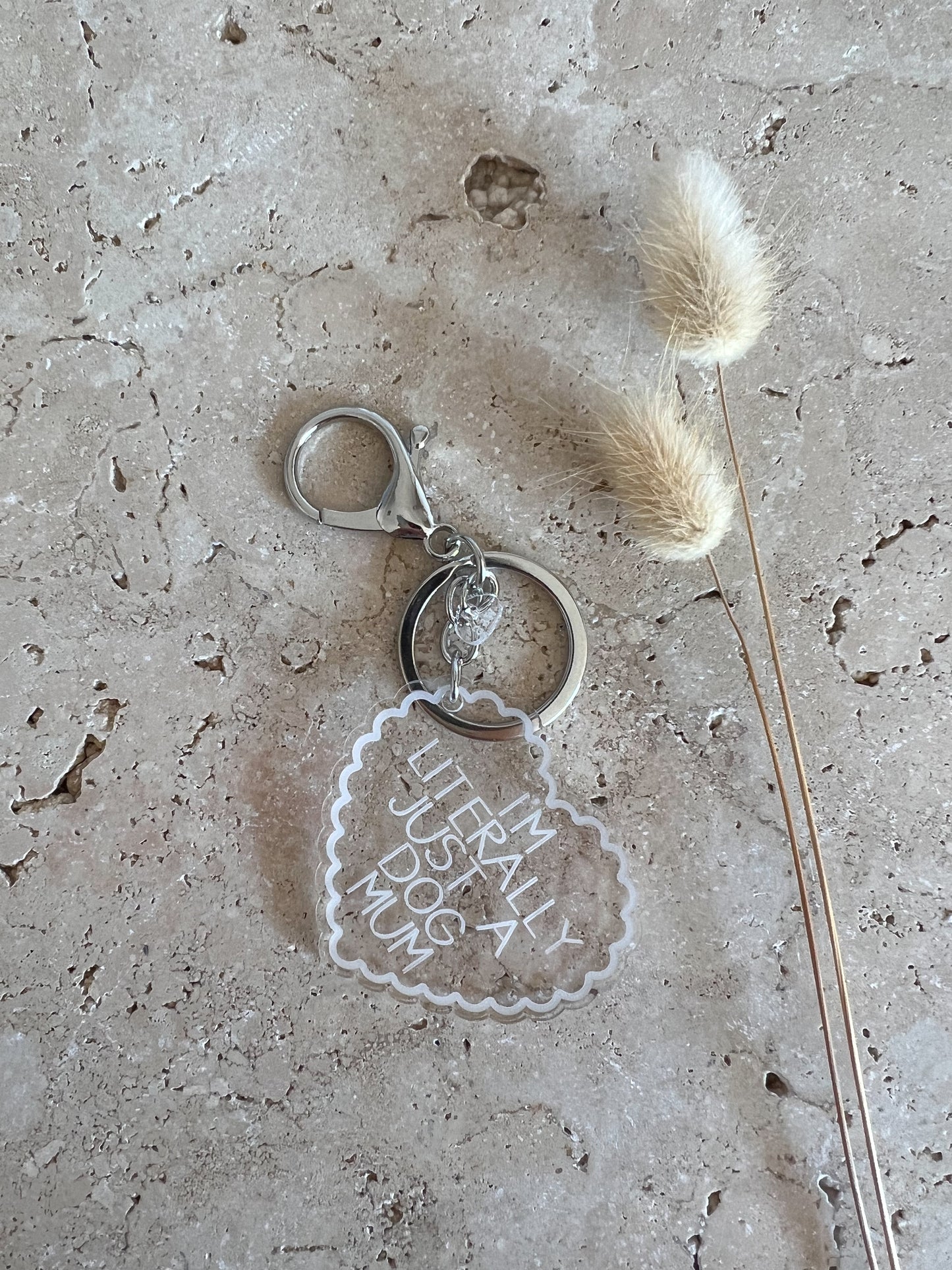 Keychain with 'I'm literally a dog mum' text on a textured surface with dried grass.