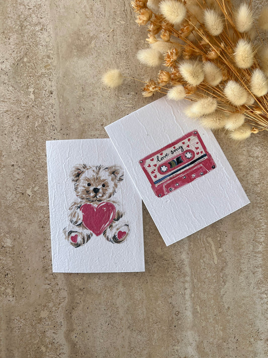 Two greeting cards on a textured surface with a teddy bear and cassette tape design by willow & sage co.
