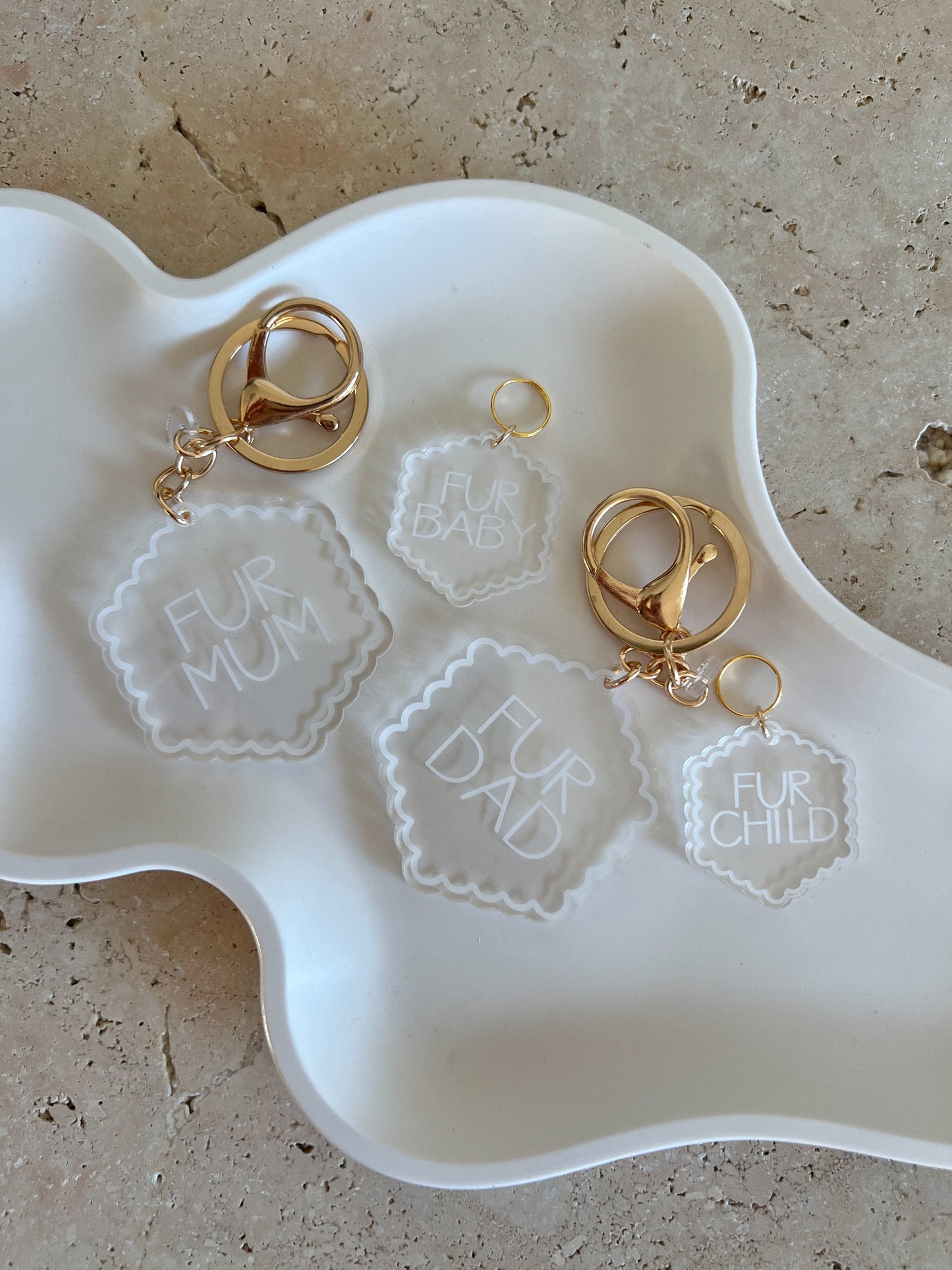 Gold pet tags with 'Fur Mum', 'Fur Dad', and 'Fur Child' engraved on a white dish.