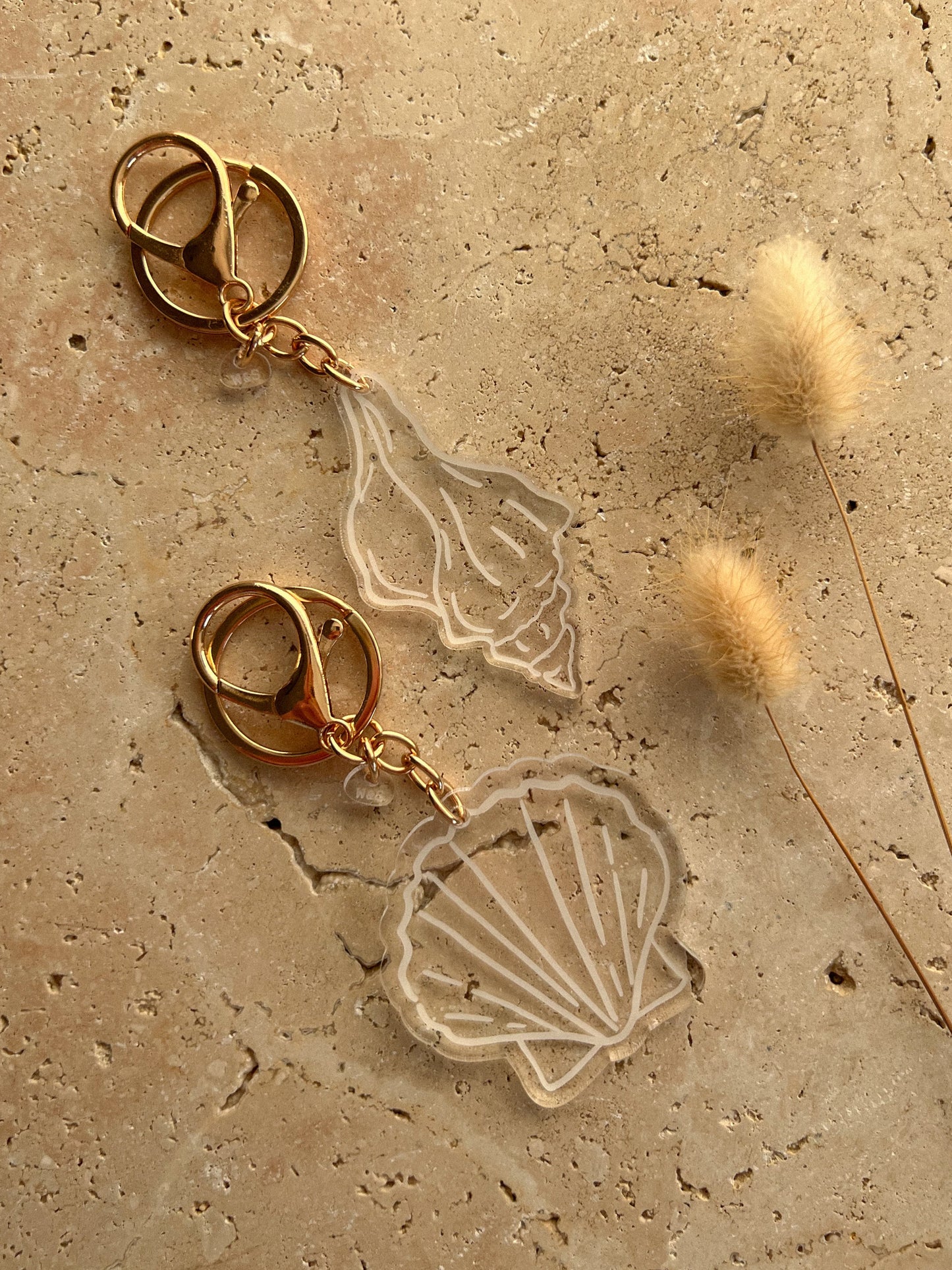 Gold keychain with shell design on a textured beige surface by Willow & sage co