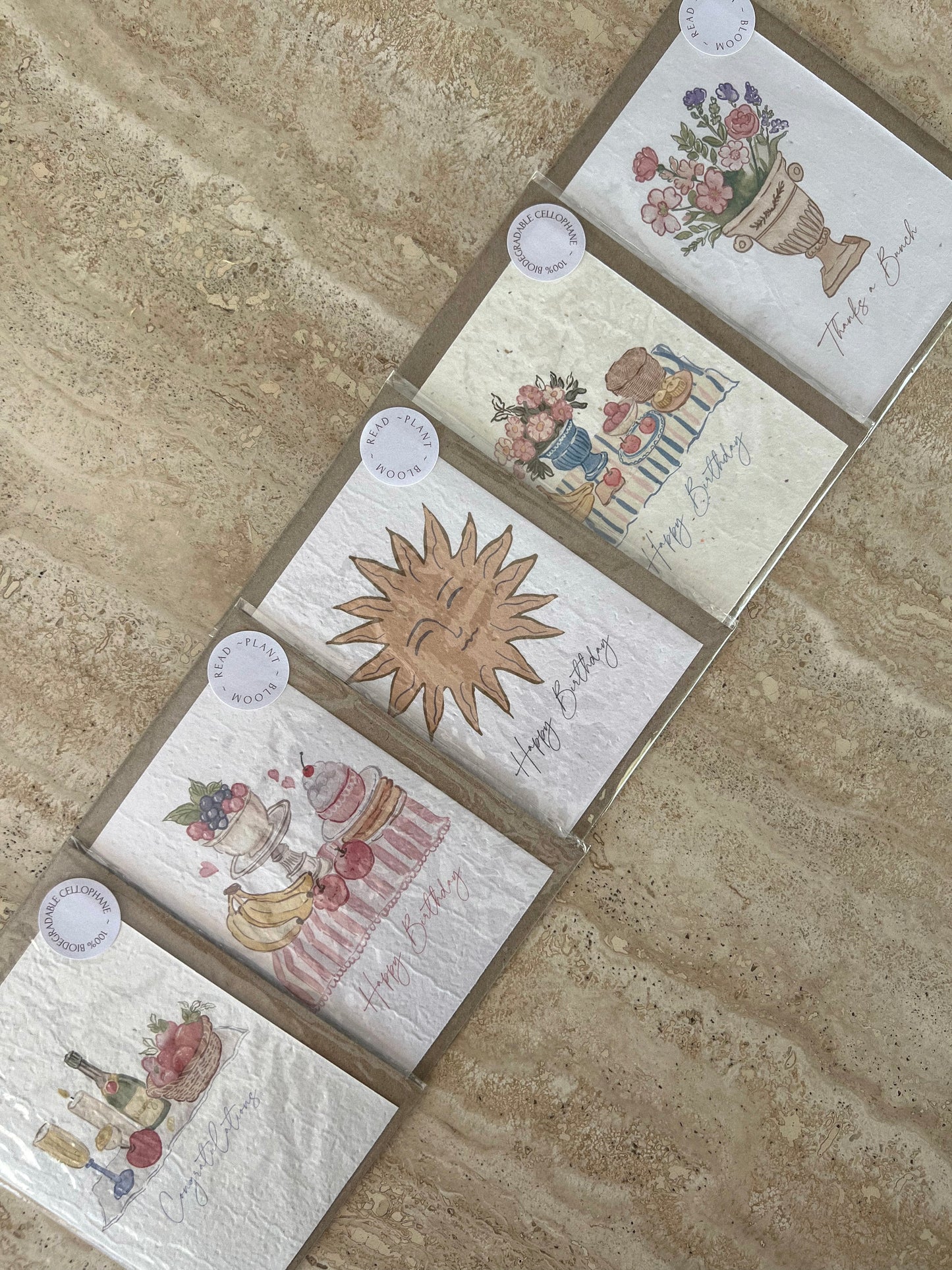 Set of plantable greeting cards by willow & sage co with floral and sun designs on a stone surface.